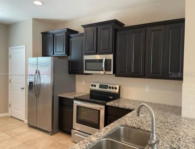 kitchen featuring sink, light stone counters, appliances with stainless steel finishes, and light tile patterned floors