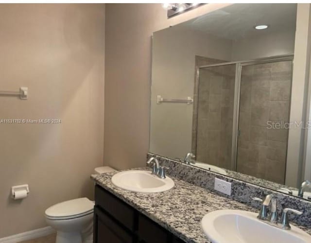 bathroom featuring toilet and dual bowl vanity