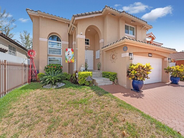 mediterranean / spanish home featuring a garage and a front lawn