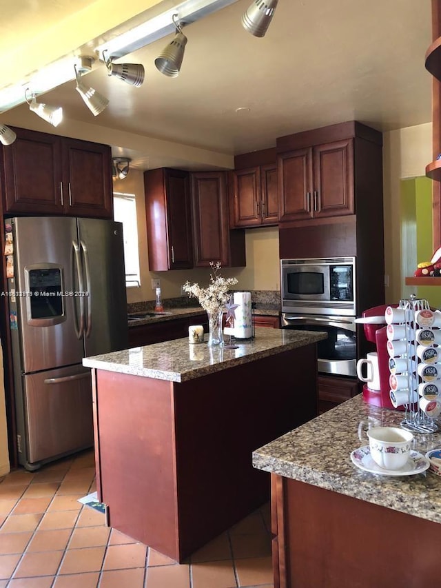 kitchen featuring a center island, light stone countertops, stainless steel appliances, and light tile patterned floors