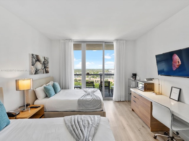 bedroom with a wall of windows, light hardwood / wood-style flooring, and access to exterior