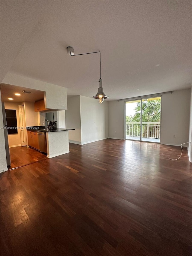 unfurnished living room featuring ceiling fan, dark hardwood / wood-style flooring, and a textured ceiling