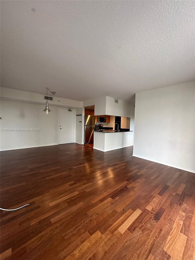 unfurnished living room featuring sink, a textured ceiling, and dark hardwood / wood-style flooring