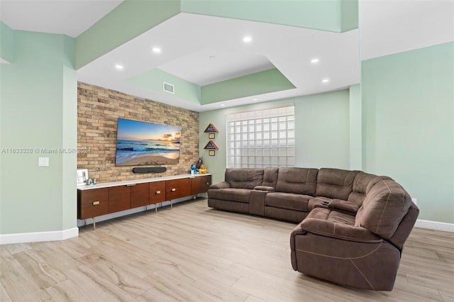 living room with a tray ceiling and light wood-type flooring