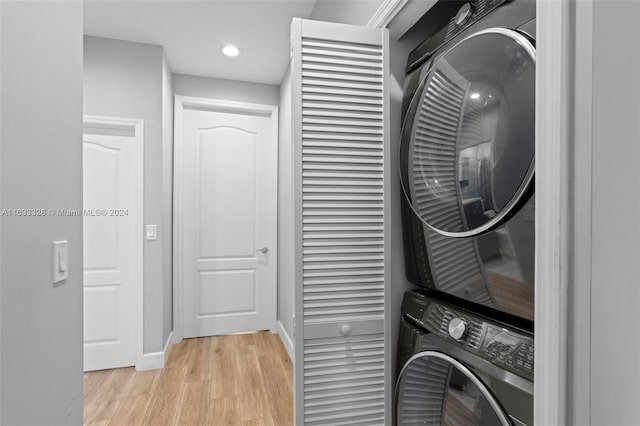 washroom with stacked washer / drying machine and light hardwood / wood-style floors