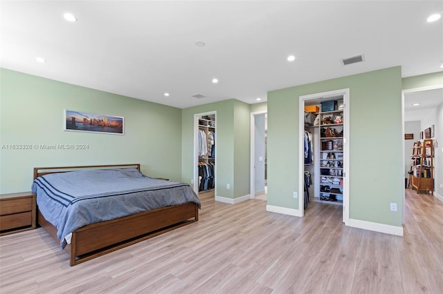 bedroom with a spacious closet, light wood-type flooring, and a closet