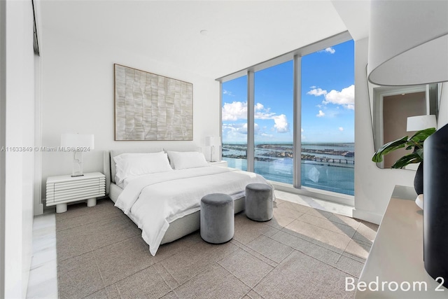 bedroom with a wall of windows, a water view, and light tile patterned floors