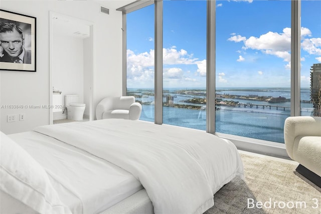 bedroom featuring multiple windows, a water view, and connected bathroom