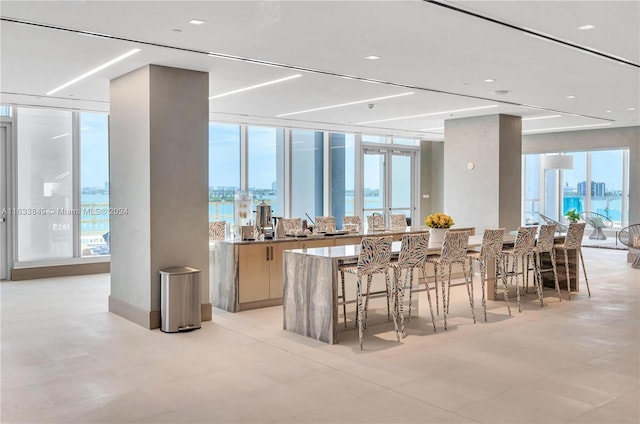 interior space featuring a water view, a wall of windows, and light tile patterned floors