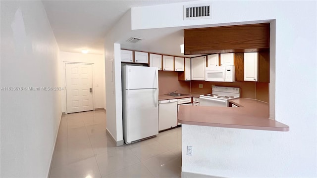 kitchen featuring light tile patterned floors, white cabinets, white appliances, sink, and kitchen peninsula