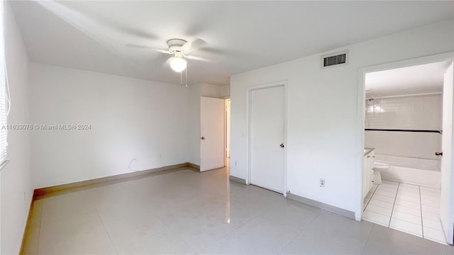 unfurnished bedroom with a closet, ensuite bath, light tile patterned floors, and ceiling fan