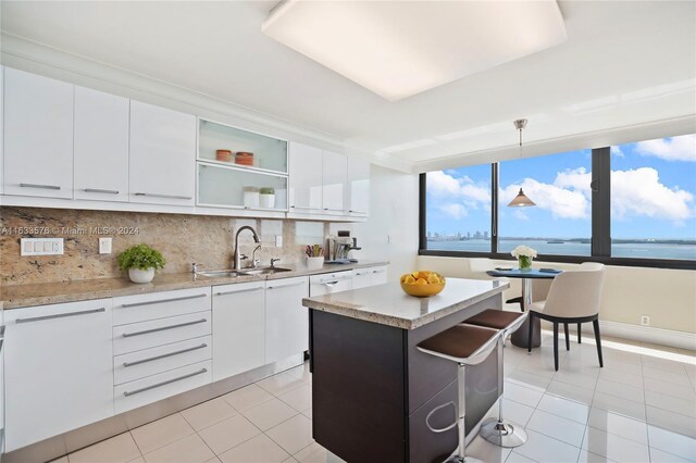 kitchen featuring decorative backsplash, light tile patterned flooring, decorative light fixtures, and sink