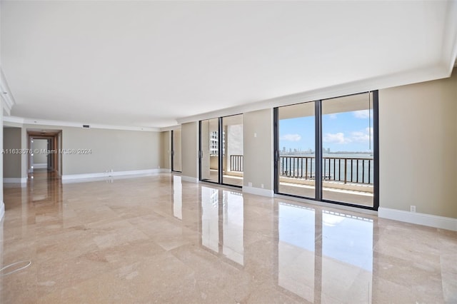 spare room with expansive windows, marble finish floor, a water view, and baseboards