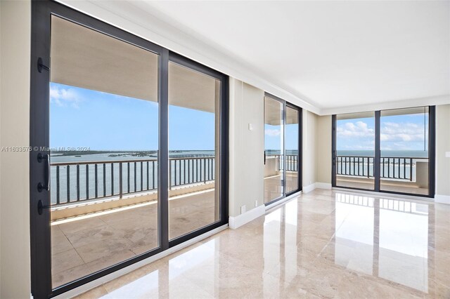 tiled empty room featuring a water view and expansive windows