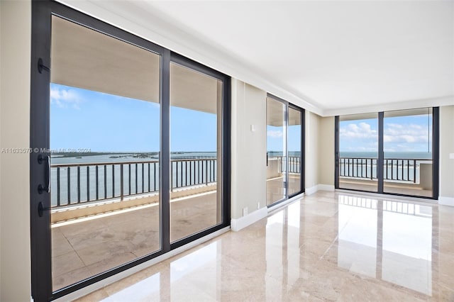 empty room with floor to ceiling windows, a water view, and baseboards