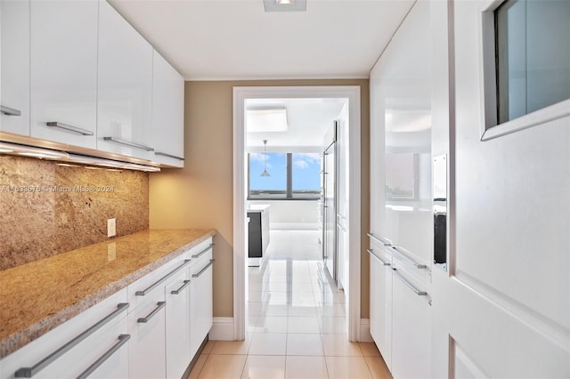 kitchen with white cabinets, light tile patterned flooring, light stone counters, and tasteful backsplash