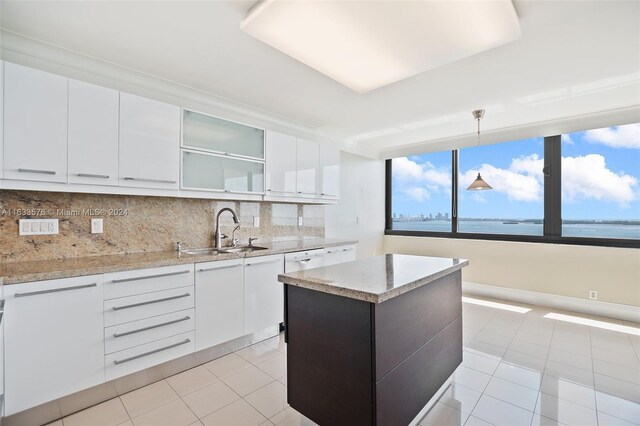 kitchen with sink, hanging light fixtures, backsplash, and light tile patterned floors