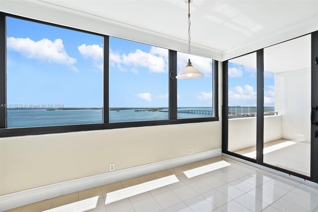 spare room with a water view and light tile patterned floors