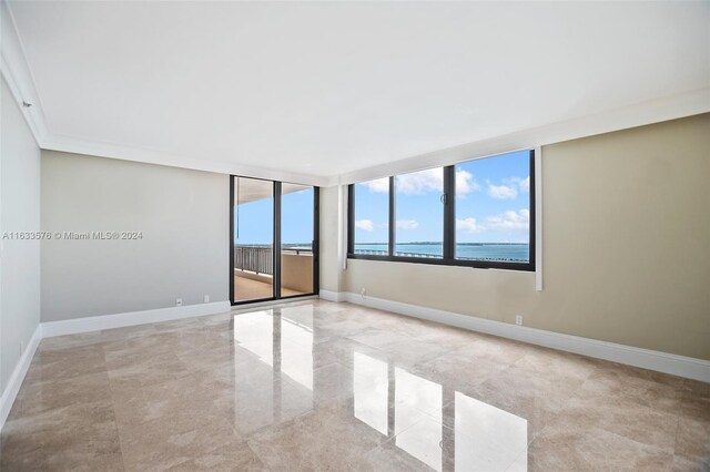 spare room featuring a water view and light tile patterned floors