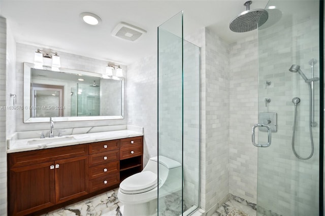 full bath featuring a stall shower, marble finish floor, tile walls, and vanity