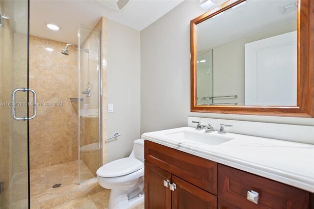 bathroom featuring tile patterned flooring, a shower with shower door, toilet, and vanity