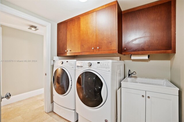 washroom with light tile patterned floors, washing machine and clothes dryer, sink, and cabinets