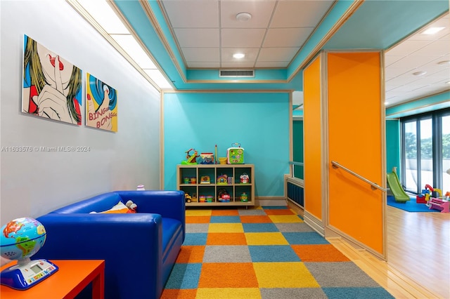 game room with a drop ceiling and light wood-type flooring