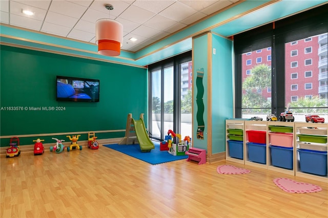 recreation room featuring ornamental molding, wood finished floors, and baseboards