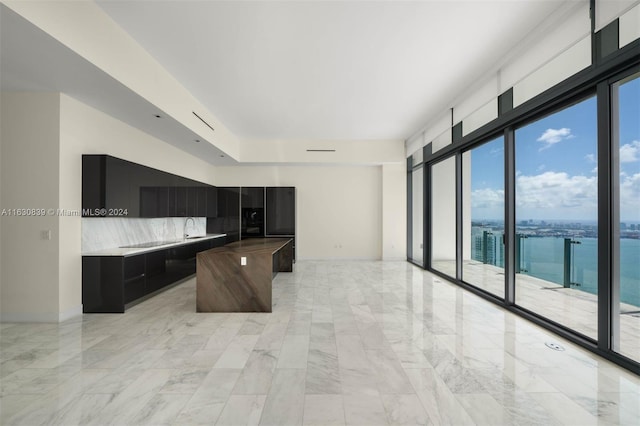 kitchen featuring a water view, decorative backsplash, sink, and a kitchen island