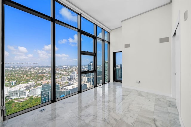 spare room featuring a towering ceiling and floor to ceiling windows