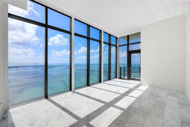 unfurnished room with expansive windows and a water view