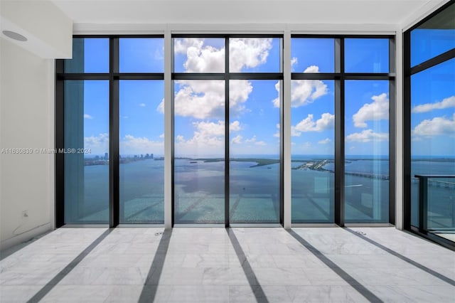 unfurnished room with a water view and expansive windows