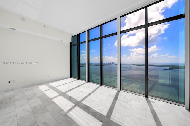 unfurnished room with a water view, floor to ceiling windows, and plenty of natural light