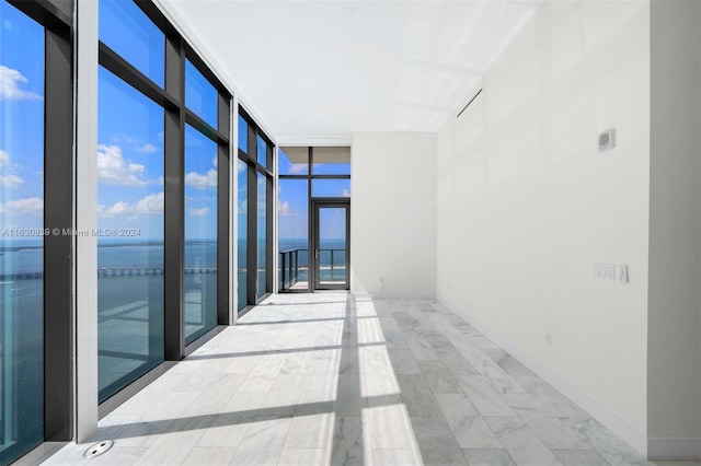 spare room featuring floor to ceiling windows and a water view