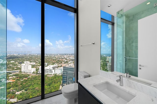 bathroom featuring expansive windows, vanity, and toilet