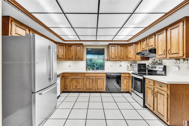 kitchen featuring appliances with stainless steel finishes, sink, light tile patterned floors, and a paneled ceiling