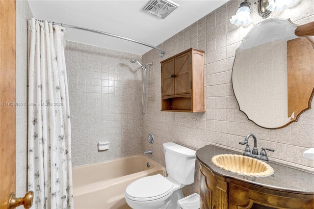 full bathroom with tile walls, shower / tub combo, vanity, and toilet