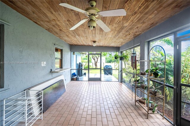 unfurnished sunroom featuring wooden ceiling and ceiling fan