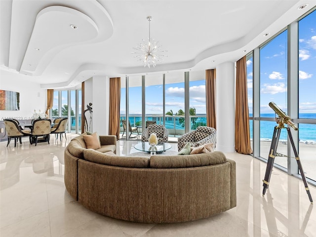 tiled living room with plenty of natural light, floor to ceiling windows, a water view, and an inviting chandelier