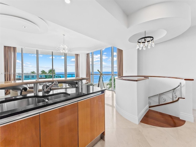 kitchen featuring a wealth of natural light, sink, a water view, and a notable chandelier