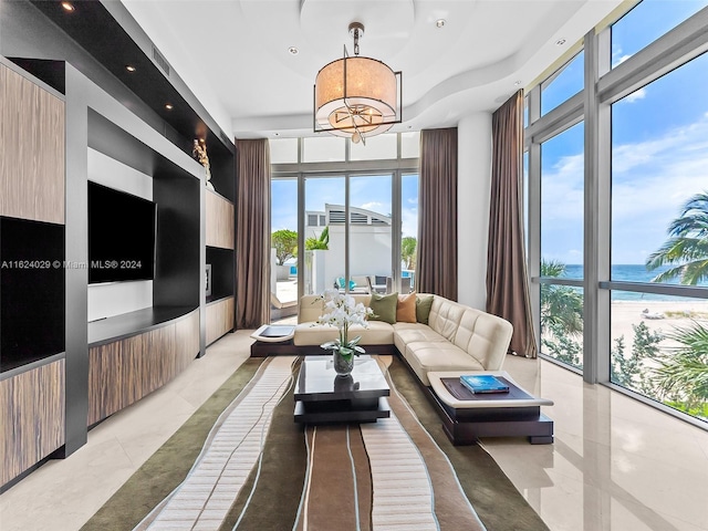 living room featuring expansive windows, a water view, and a notable chandelier