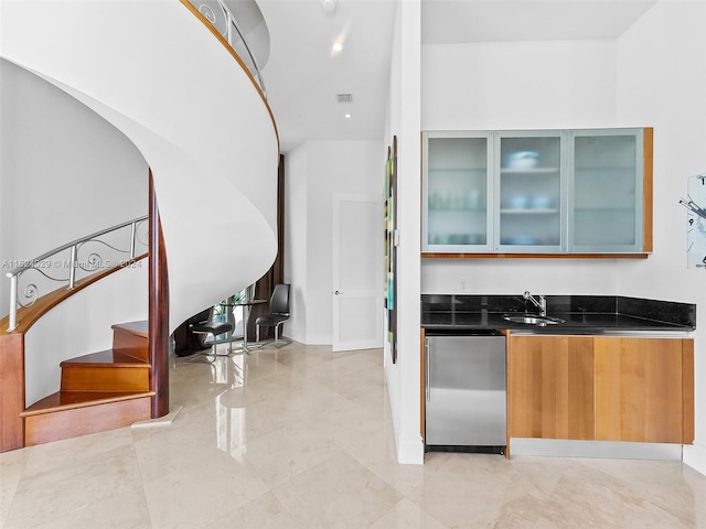 bar featuring stainless steel fridge, sink, and dark stone counters