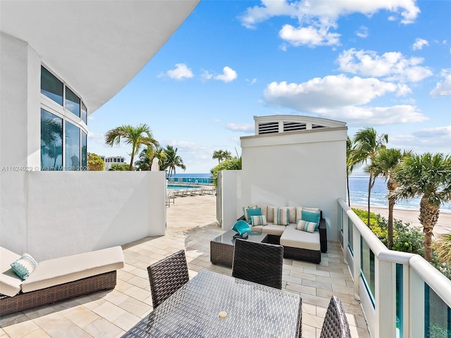 view of patio with outdoor lounge area, a balcony, a water view, and a view of the beach