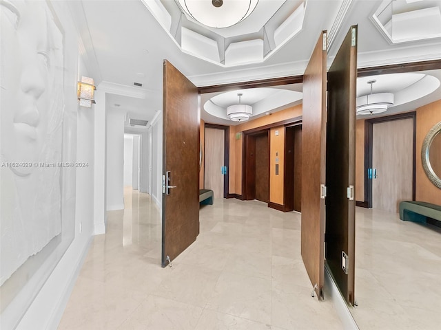 hall with a raised ceiling, ornamental molding, and elevator