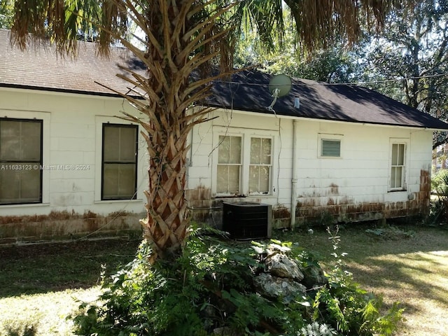 exterior space with central AC and a lawn