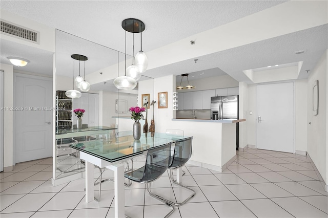 kitchen featuring white cabinetry, stainless steel fridge with ice dispenser, a raised ceiling, a breakfast bar, and light tile patterned floors