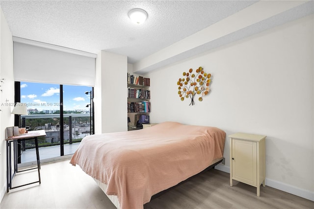 bedroom featuring a textured ceiling, access to outside, and light wood-type flooring