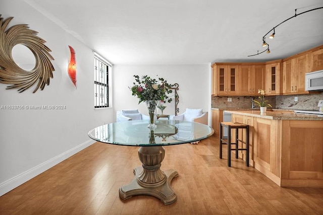 dining space with sink, track lighting, and light hardwood / wood-style floors