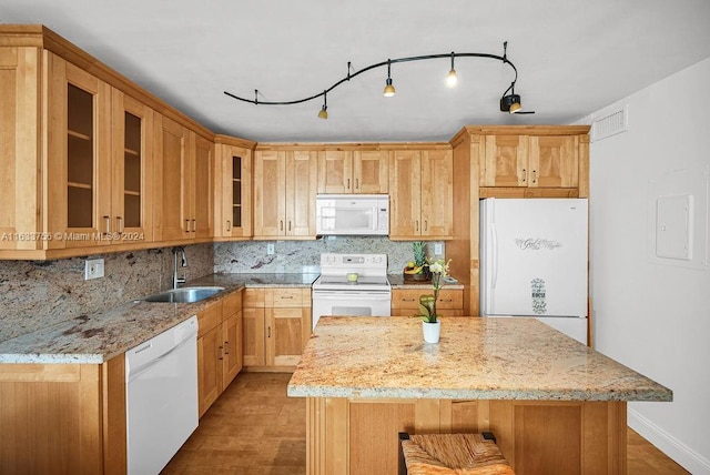 kitchen featuring sink, light stone counters, backsplash, and white appliances