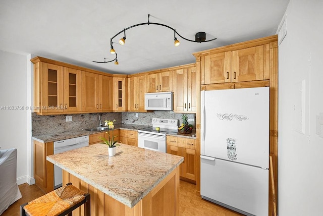 kitchen featuring sink, a center island, white appliances, light stone countertops, and decorative backsplash